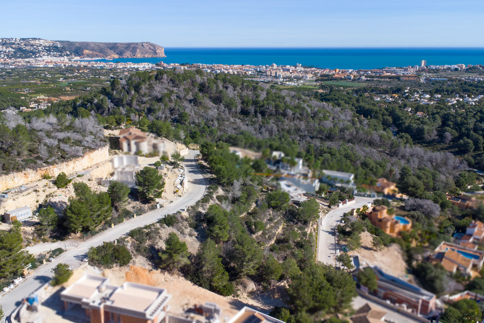 Luftbild der Erschließung Tosalet 5 in Jávea mit Hanggrundstücken, Pinienbestand und weitem Blick über das Mittelmeer bis hin zum Kap San Antonio.