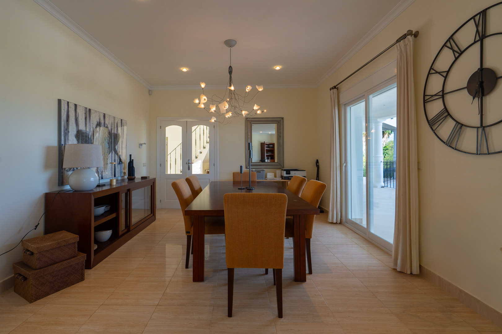 Eleganter Essbereich mit Massivholztisch, senfgelben Polsterstühlen und direktem Terrassenzugang durch große Glasschiebetüren.
