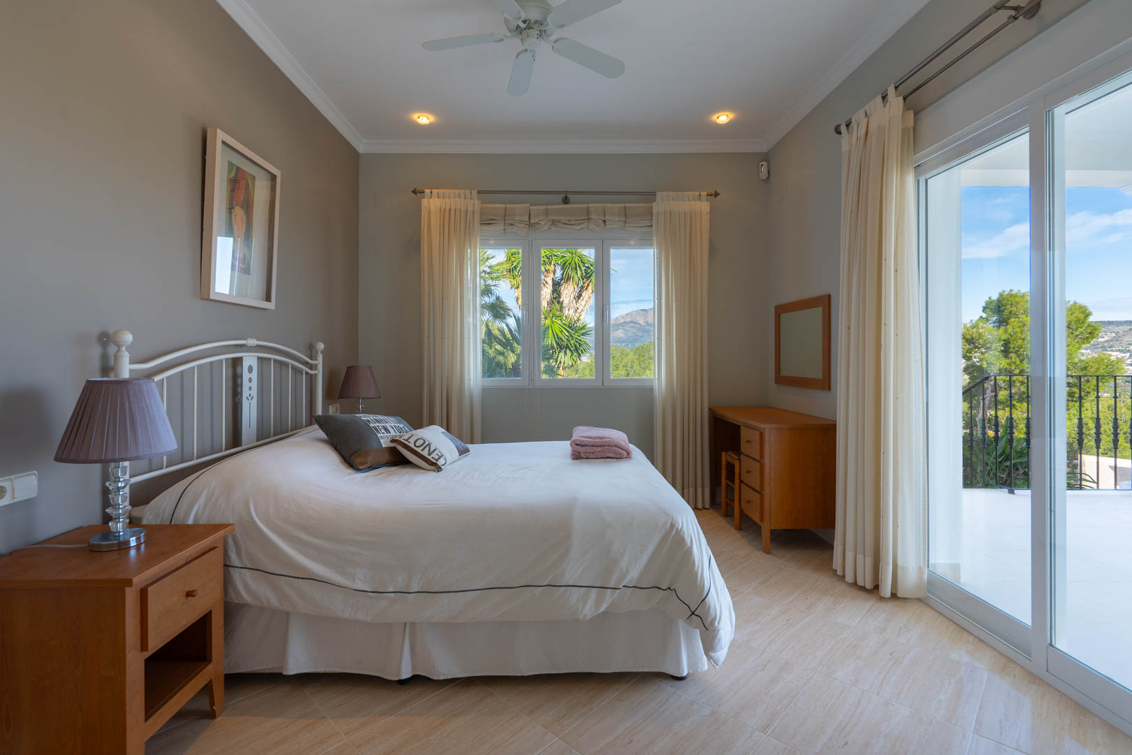 Helles Schlafzimmer mit Fliesenboden, Holzmöbeln und direktem Zugang zur Terrasse mit Blick auf den Montgó und die mediterrane Landschaft.