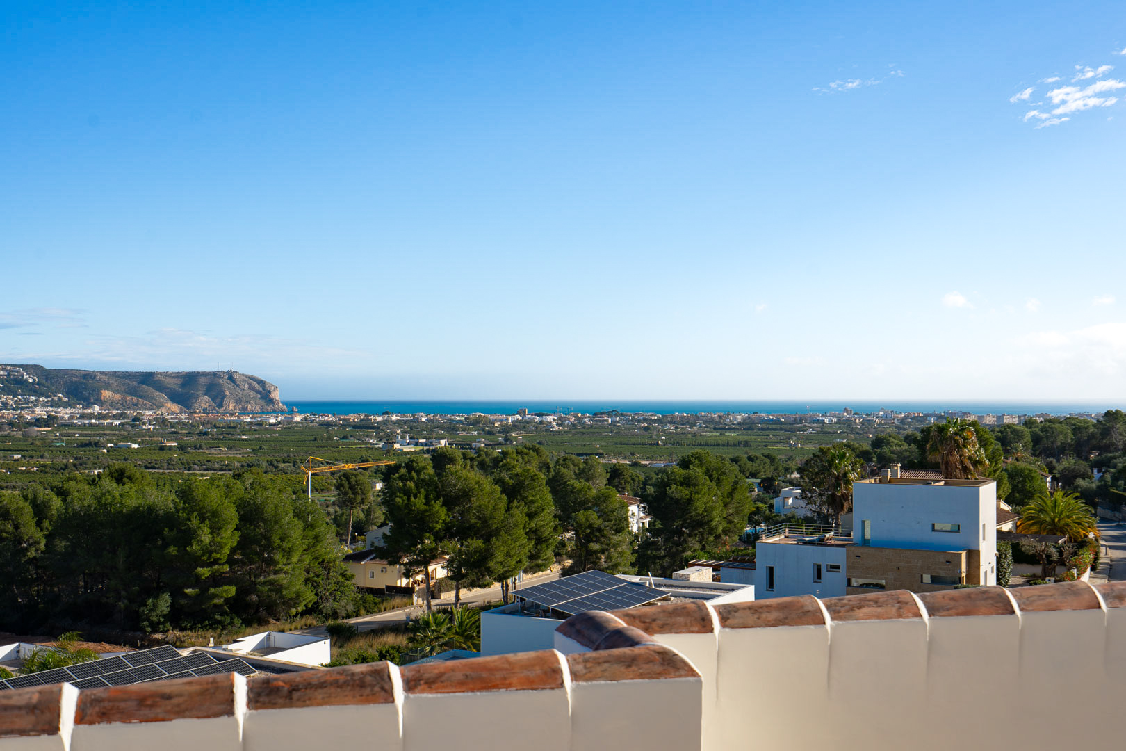 Panoramablick von der oberen Terrasse auf das Mittelmeer und die Küste, mit der Silhouette der Landzunge und der lokalen mediterranen Vegetation.