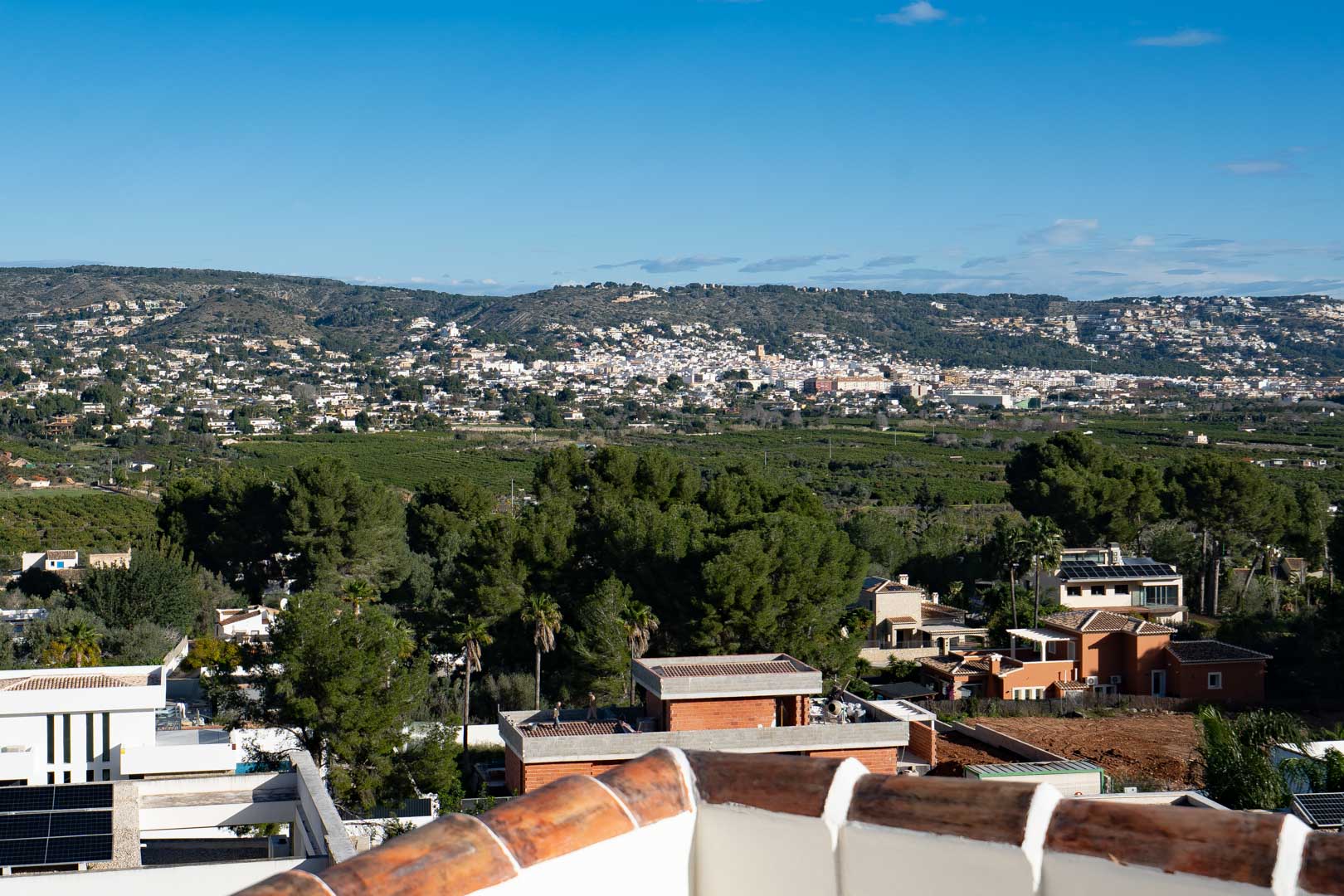 Panoramablick von der oberen Terrasse über das Tal und die Hügel, der die mediterrane Landschaft und die gewachsene Wohnumgebung der Region zeigt.