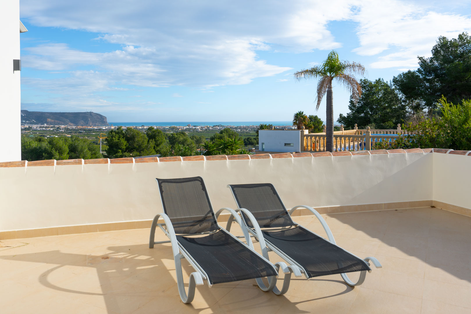 Sonnenterrasse mit zwei modernen Liegen und Panoramablick auf das Mittelmeer und das Montgó-Massiv an der Costa Blanca.