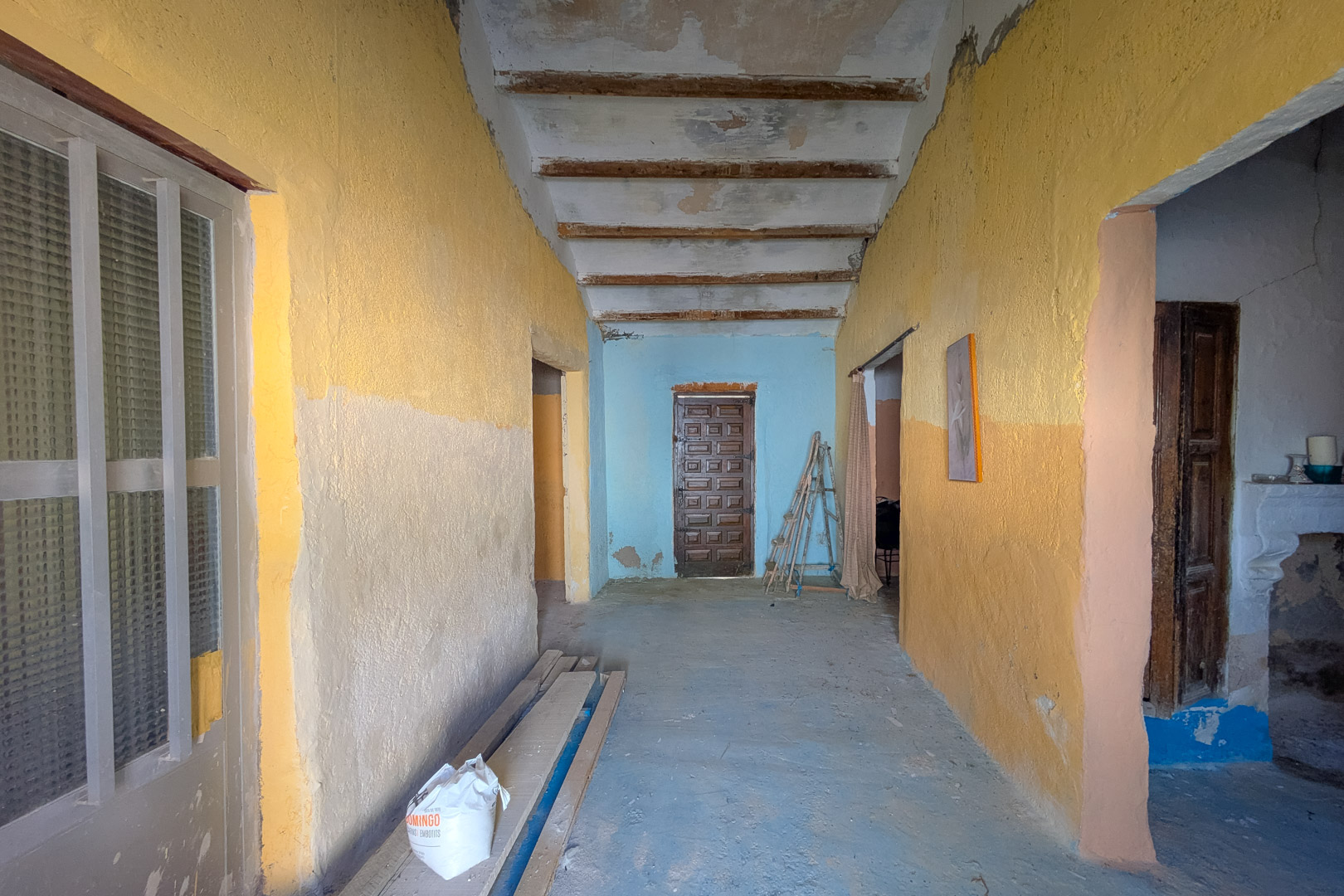 Innenflur mit hohen Decken, sichtbaren Holzbalken und rustikalen Wänden, die den ursprünglichen Charakter und das Renovierungspotenzial widerspiegeln.