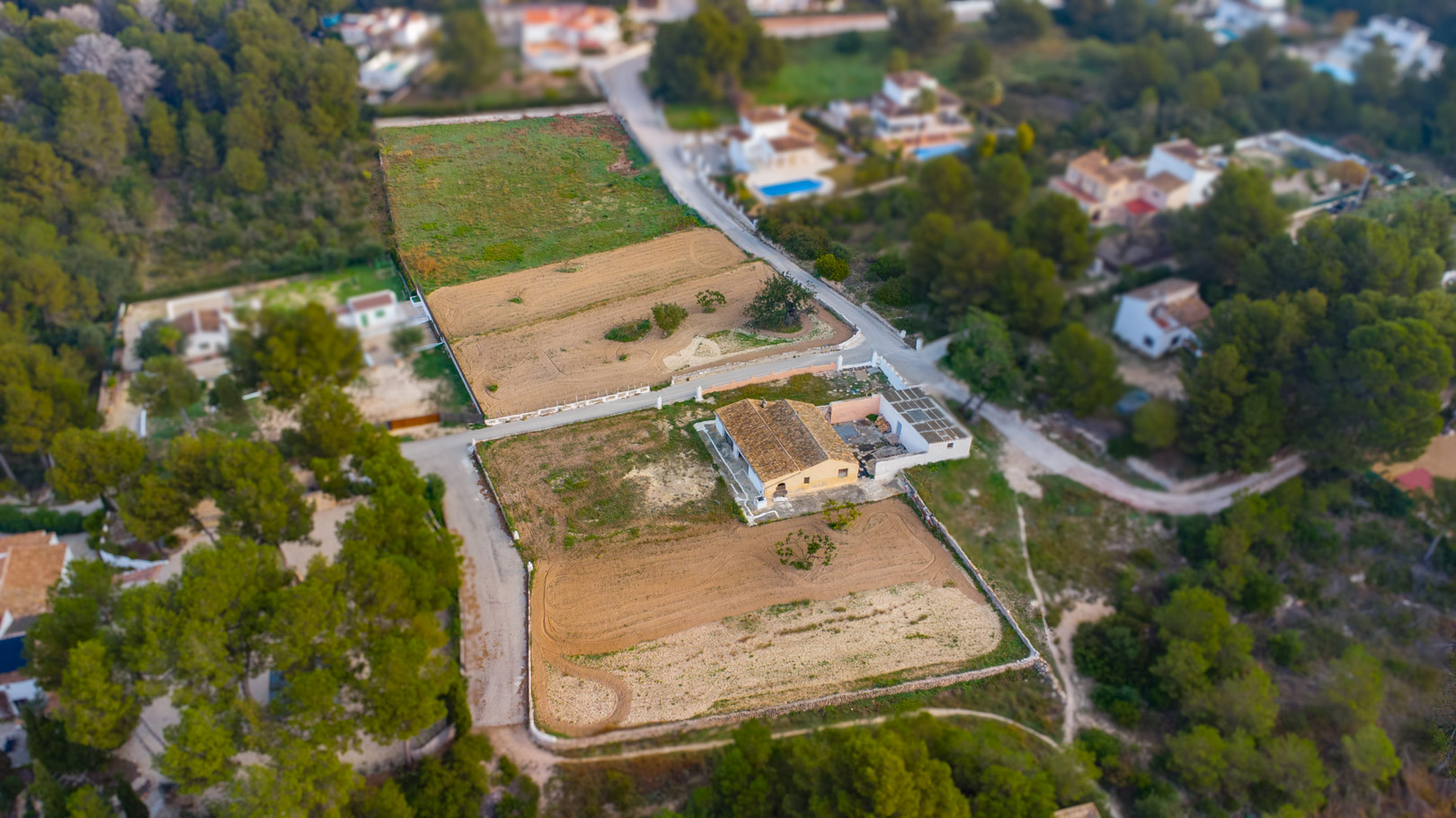 Luftaufnahme der traditionellen Finca und der weitläufigen, flachen rustikalen Grundstücke, umgeben von mediterraner Vegetation und Pinienwäldern in Jávea.