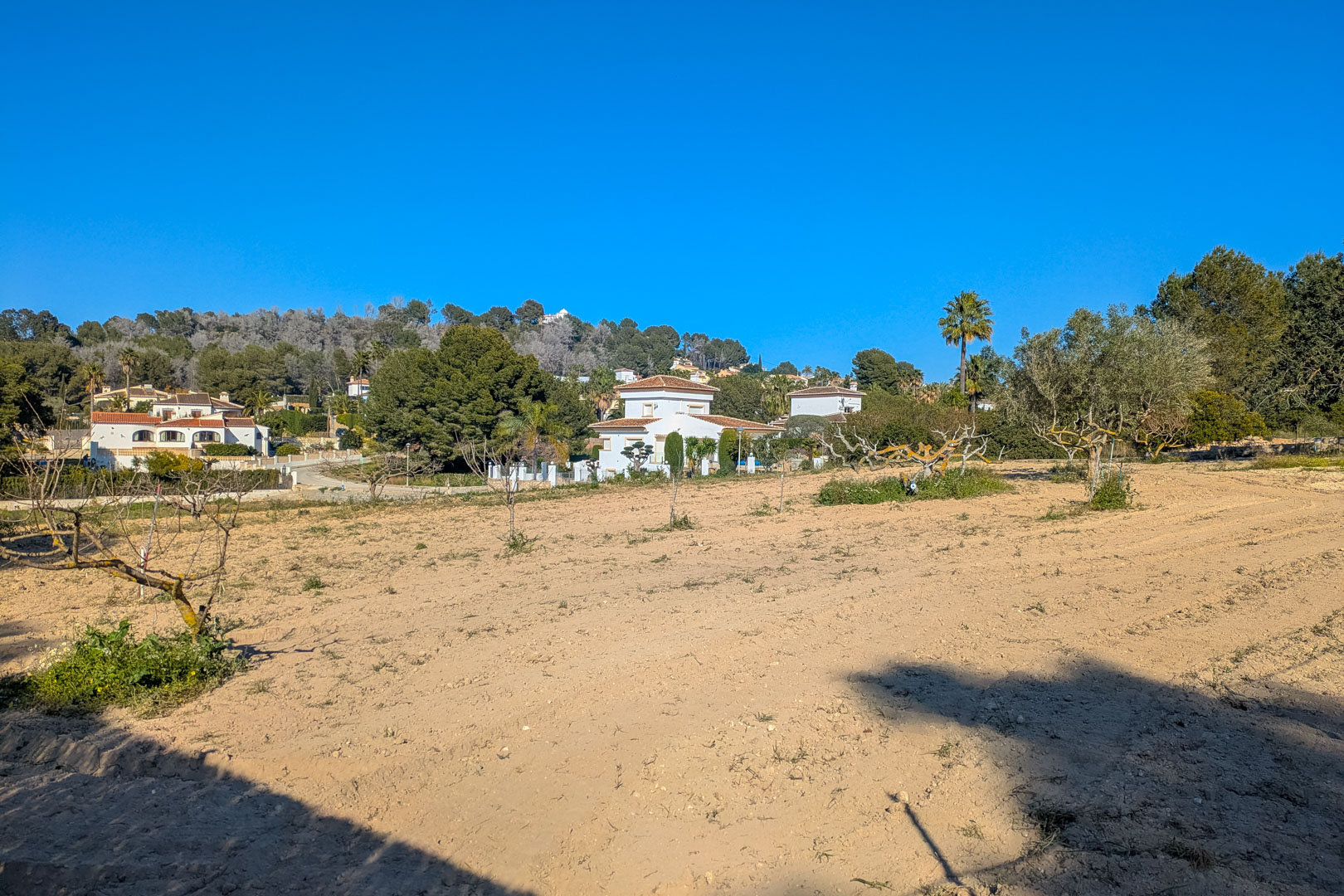 Panoramablick auf das weitläufige, flache rustikale Grundstück, umgeben von mediterraner Vegetation mit freiem Blick auf die Hügel und Nachbarvillen.