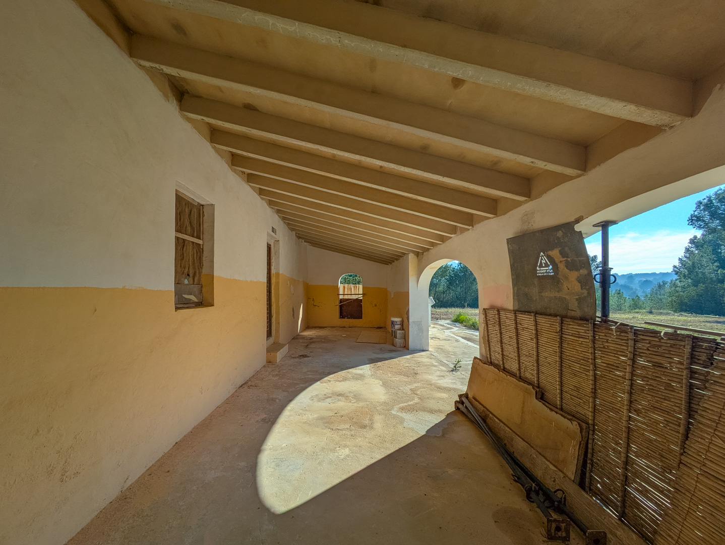 Traditionelle überdachte Veranda mit sichtbaren Holzbalken und ockerfarbenen Wänden mit Blick auf die ländliche Umgebung von Jávea.