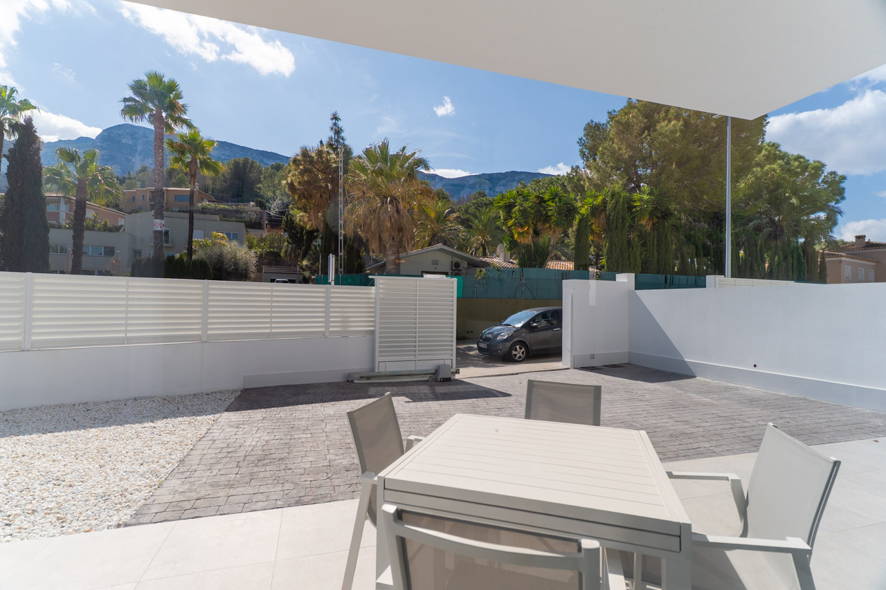 Außenbereich mit Essplatz und privatem Parkplatz. Die Terrasse bietet einen freien Blick auf das Montgó-Massiv in einer modernen, architektonischen Umgebung.