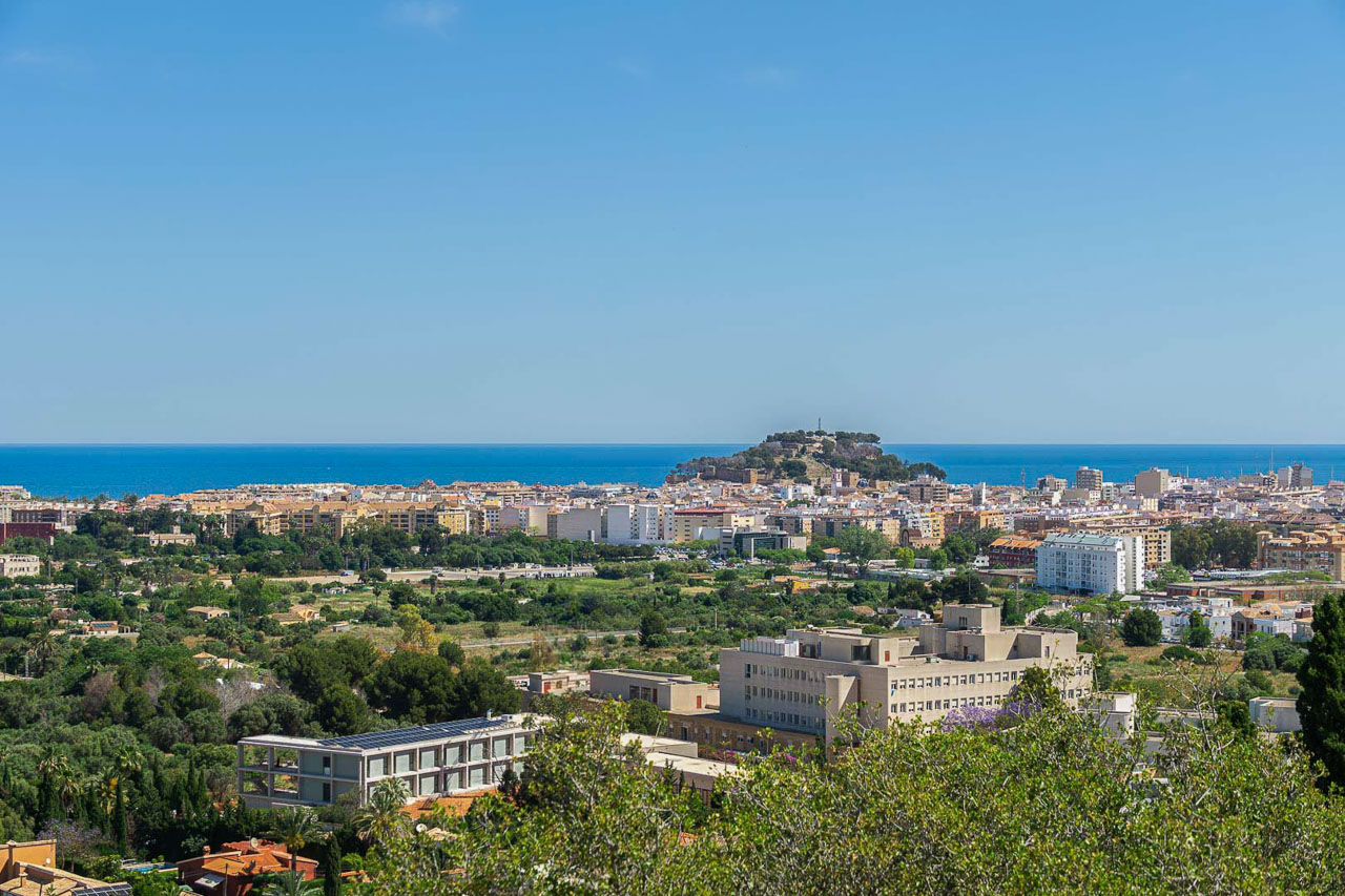 Panoramablick über Dénia mit der historischen Burg und dem Mittelmeer am Horizont. Die erhöhte Lage verdeutlicht die Nähe zum Stadtzentrum und zur Küste.