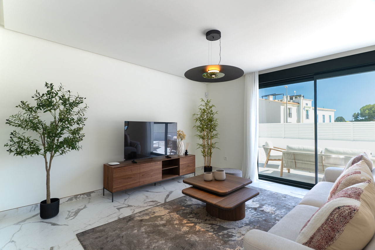 Zeitgenössisches Wohnzimmer mit Marmoreffekt-Bodenfliesen, minimalistischen Holzmöbeln und großen Glasschiebetüren, die zur privaten Terrasse führen.