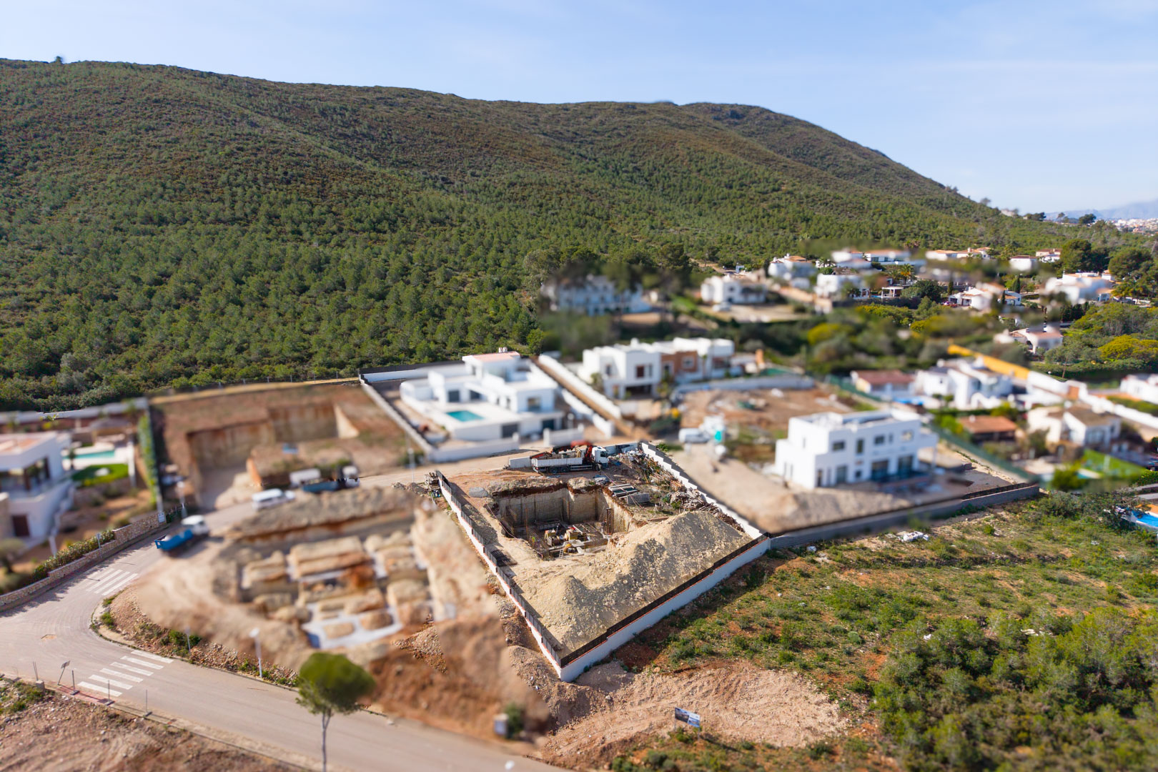 Luftaufnahme des Baugrundstücks in Valsol, die den Aushub und die Fundamentphase inmitten moderner Villen und der naturnahen Umgebung von Jávea zeigt.