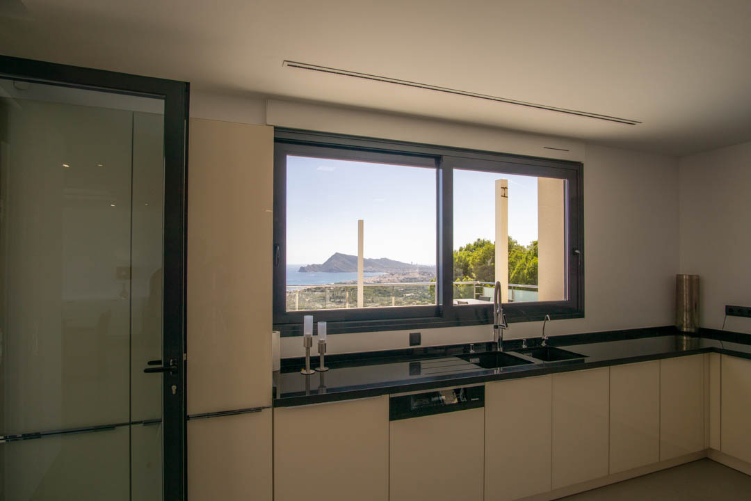 Moderne Küche mit schwarzer Granitarbeitsplatte und großem Panoramafenster mit Blick auf die Bucht von Altea und das Mittelmeer.