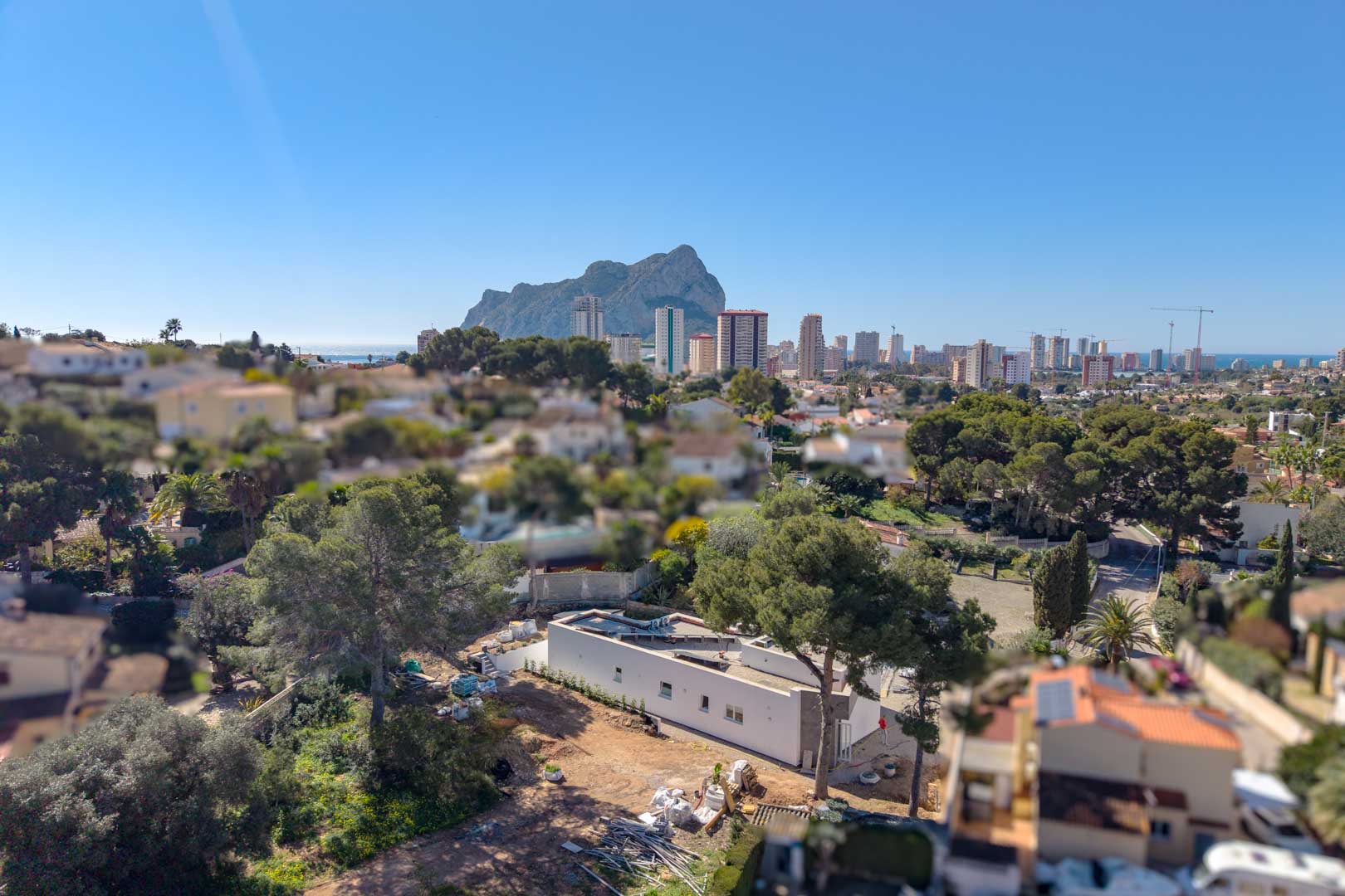 Luftaufnahme der minimalistischen Villa im Bau, die das einstöckige Design und die exklusive Lage mit Blick auf den Peñón de Ifach und die Skyline von Calpe hervorhebt.