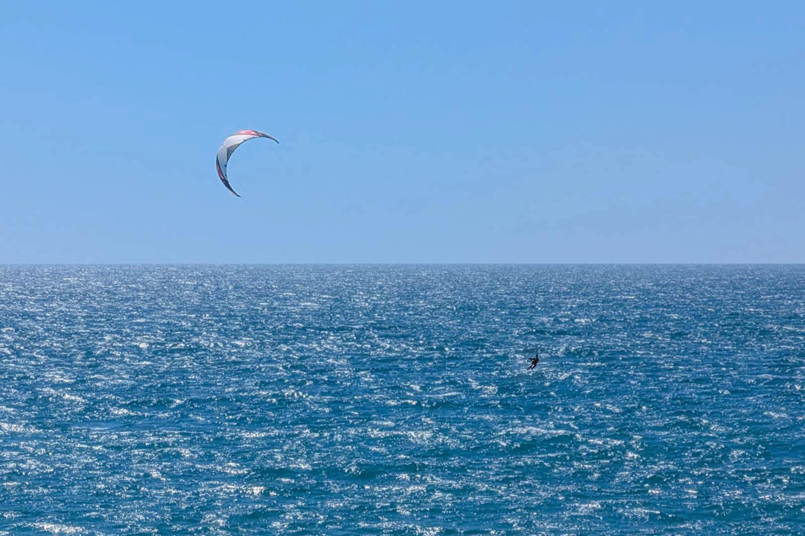 Panoramablick auf das Mittelmeer bei Calpe mit einem Kitesurfer unter strahlend blauem Himmel, ideal für Wassersportliebhaber.