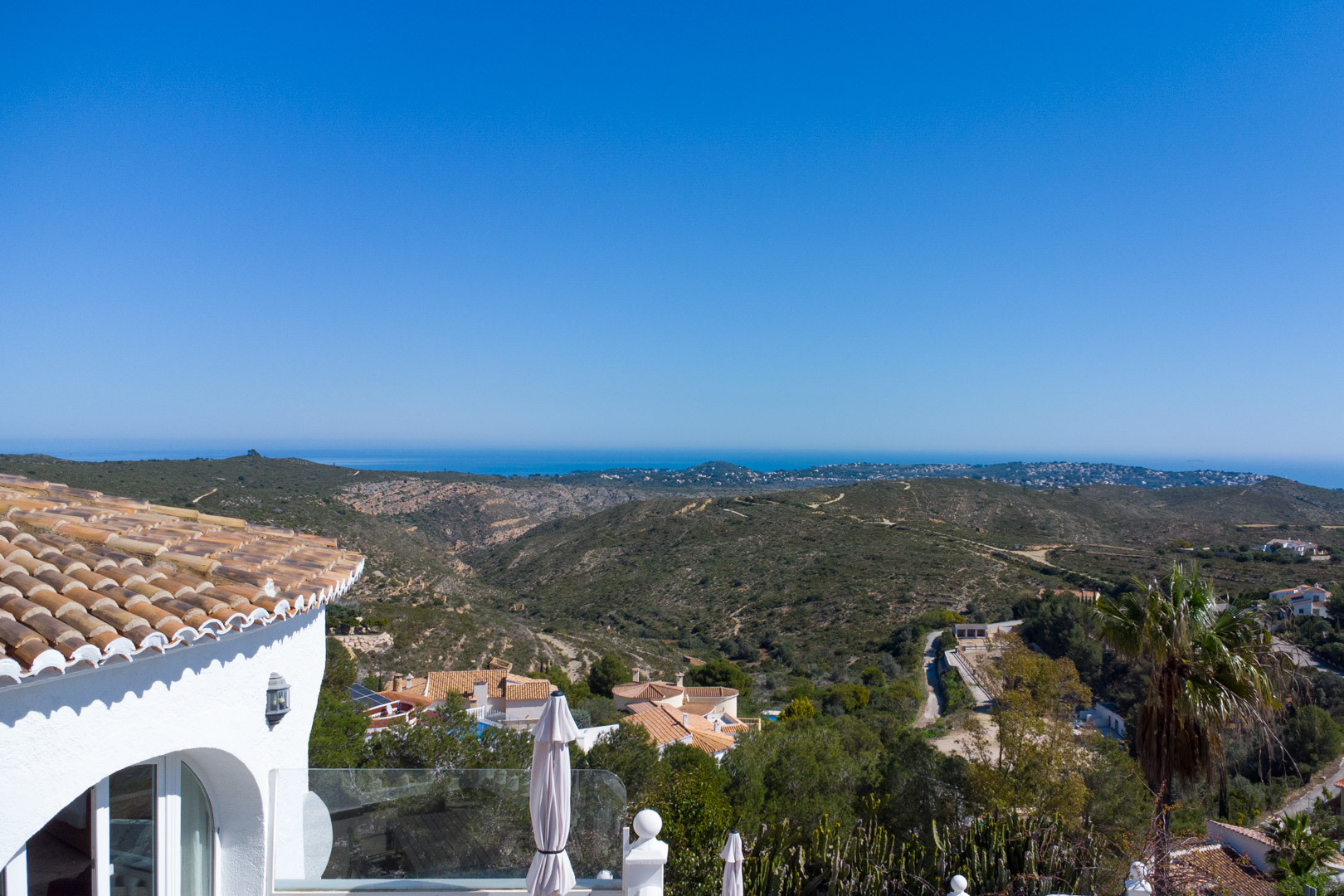 Panoramablick von der Villa auf den Naturpark Granadella und das Mittelmeer, mit traditioneller Architektur, Terrakottadächern und weißer Fassade.