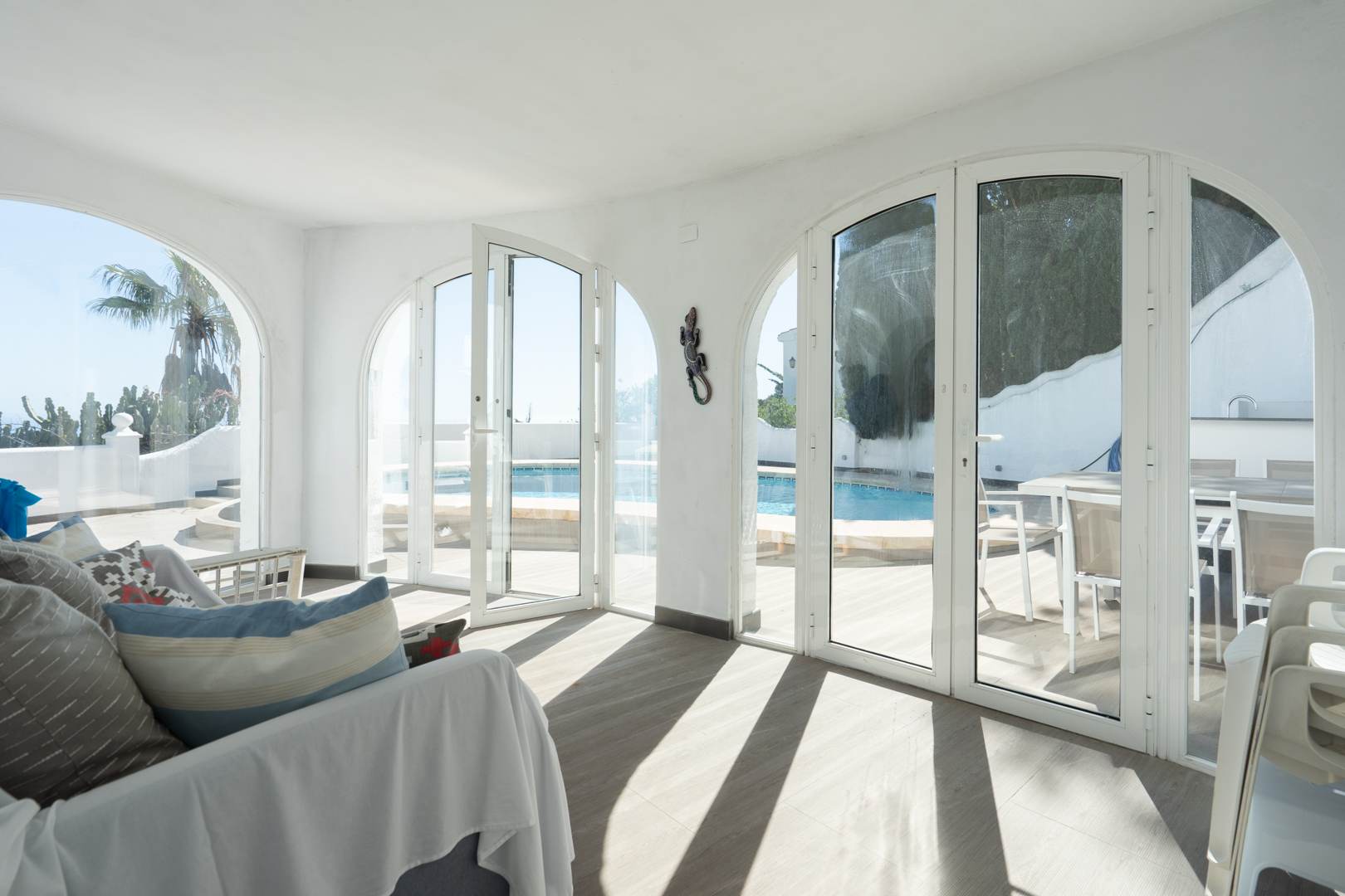Verglaste Naya mit großen Rundbogentüren, die einen direkten Zugang zur Poolterrasse und zum Essbereich im Freien bieten.