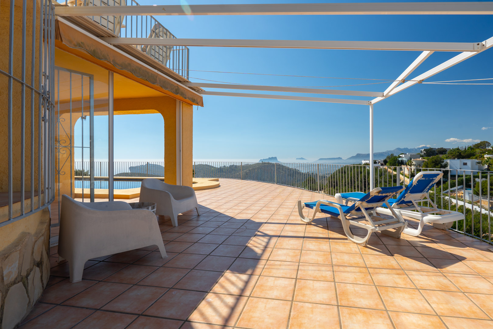 Große Sonnenterrasse mit Terrakottafliesen, Metallpergola und Panoramablick auf das Mittelmeer und die Bernia-Bergkette.