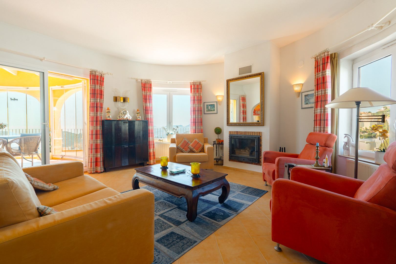 Helles Wohnzimmer mit Einbaukamin, Terrakotta-Fliesenboden und direktem Zugang zur Naya und Sonnenterrasse durch große Glasschiebetüren.