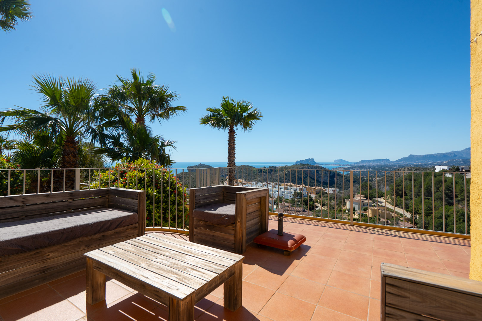 Solarium-Terrasse mit rustikalen Holzmöbeln und Panoramablick auf das Mittelmeer, den Peñón de Ifach und die Küste von Calpe.