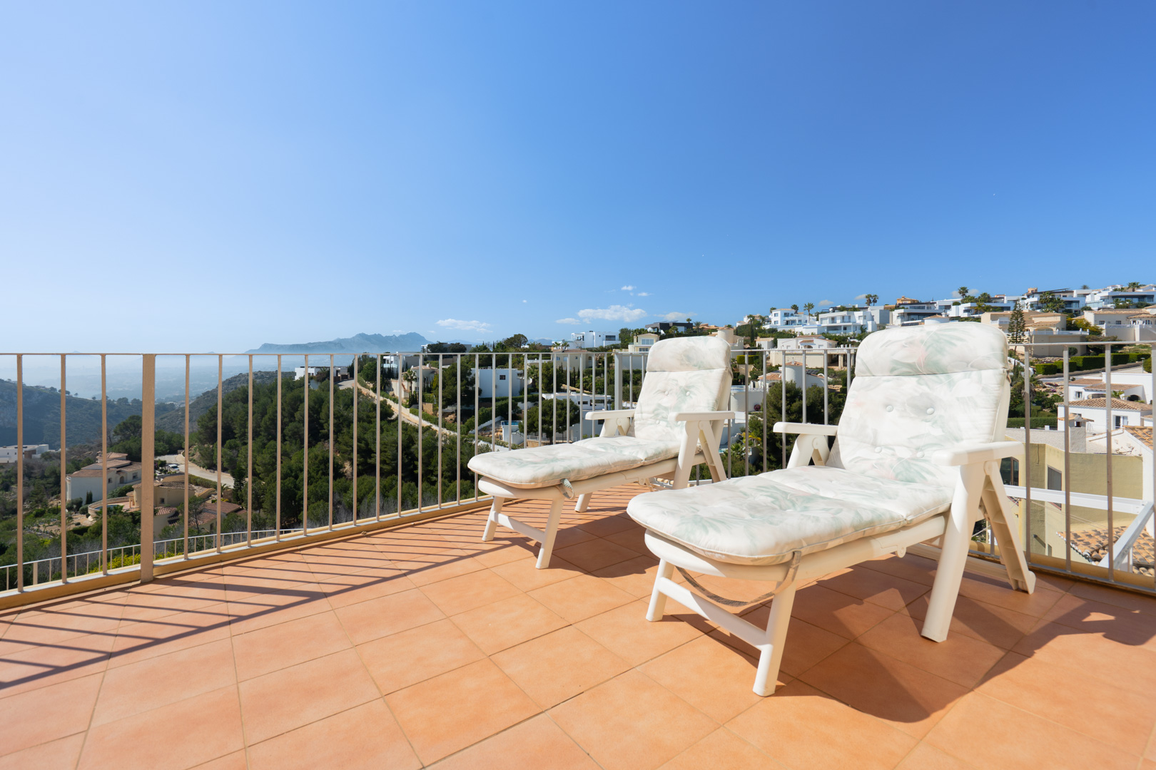 Solarium-Terrasse mit Terrakotta-Fliesen und weißem Geländer, die einen Panoramablick auf die Mittelmeerküste und die umliegenden Gebirgsketten bietet.