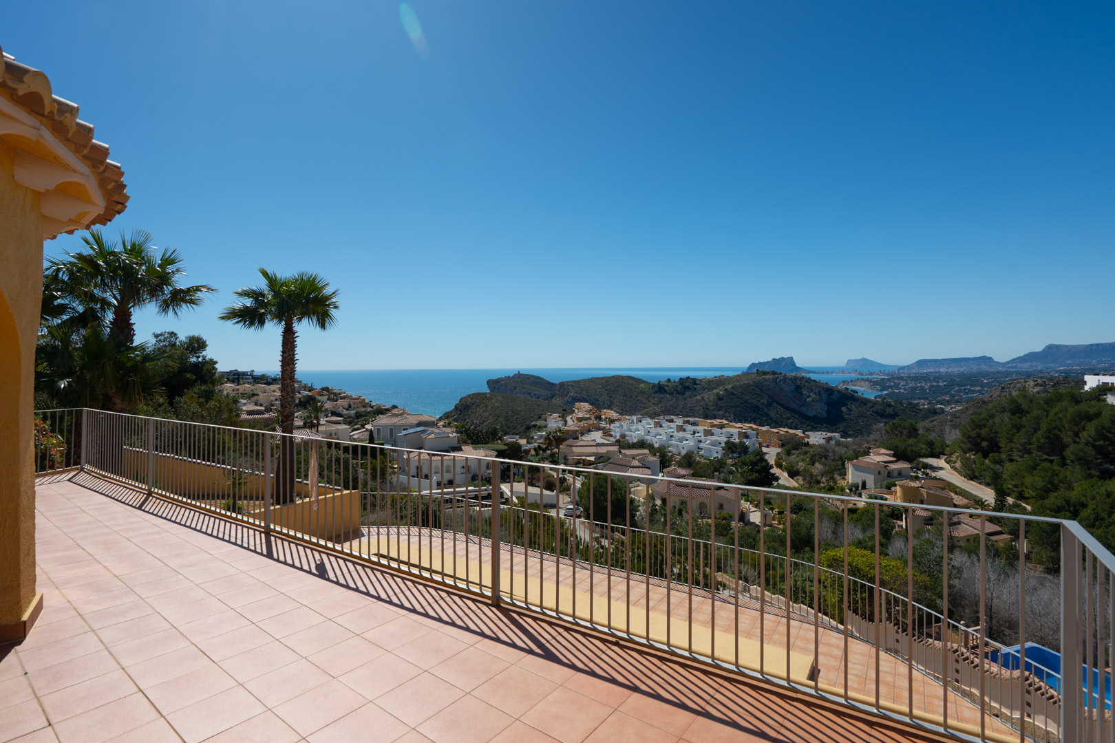 Weitläufige Sonnenterrasse mit Metallgeländer und Panoramablick auf das Mittelmeer, den Peñón de Ifach und die umliegende Küstenlandschaft.