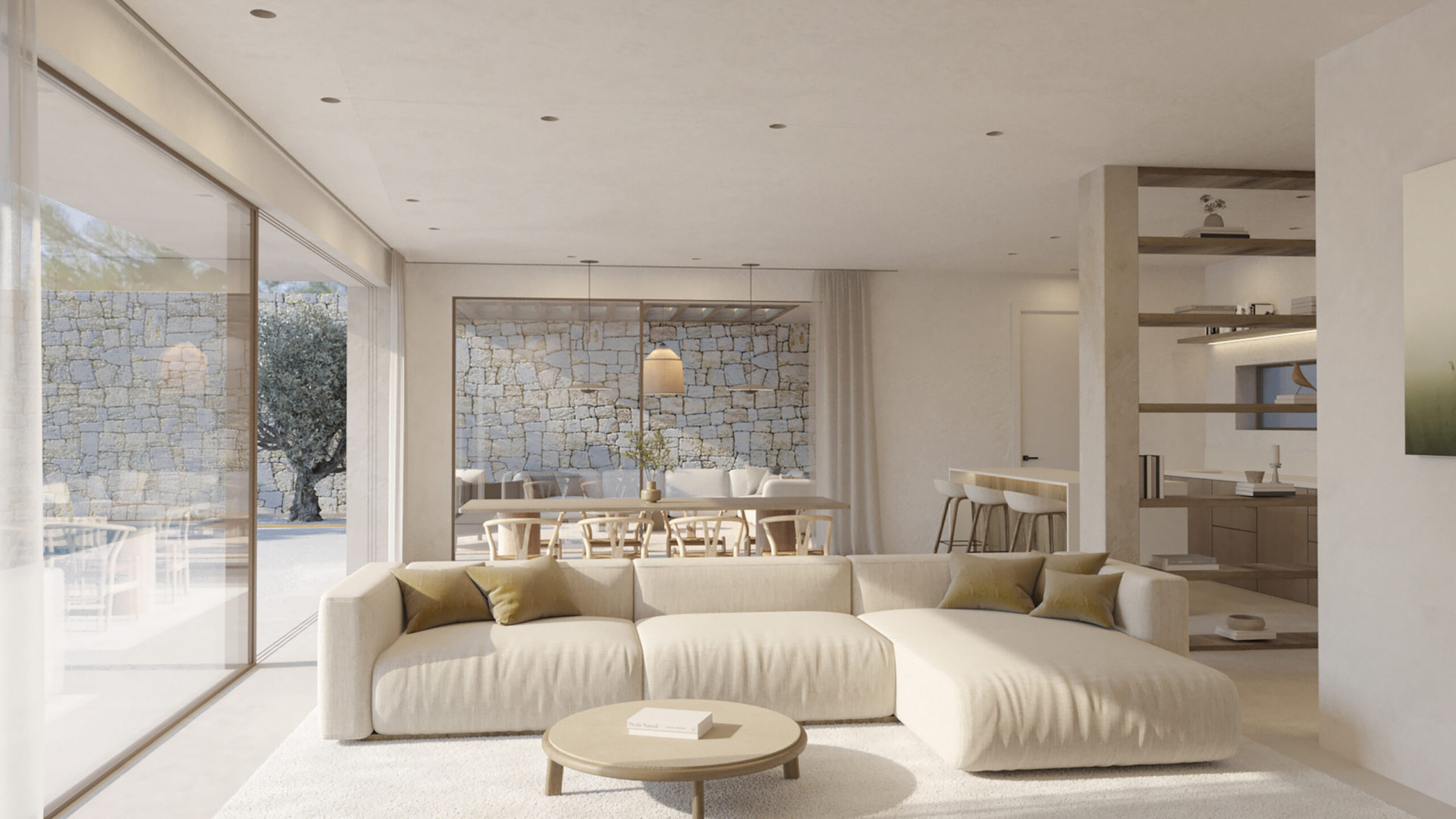 Geräumiger Wohnbereich mit hellem Ecksofa und rundem Couchtisch. Große Glastüren führen zu einer Außenterrasse mit Natursteinmauer und altem Olivenbaum.