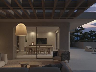 Einladender Außenwohnbereich unter einer Holzpergola mit modernen Sofas und Hängelampe, verbunden mit einem eleganten Essbereich und Bergblick bei Dämmerung.