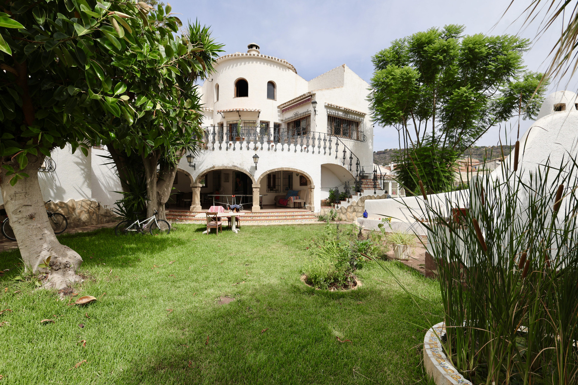 Blick auf den Vorgarten mit Rasen, Grün und der weißen Fassade der Villa in Javea.
