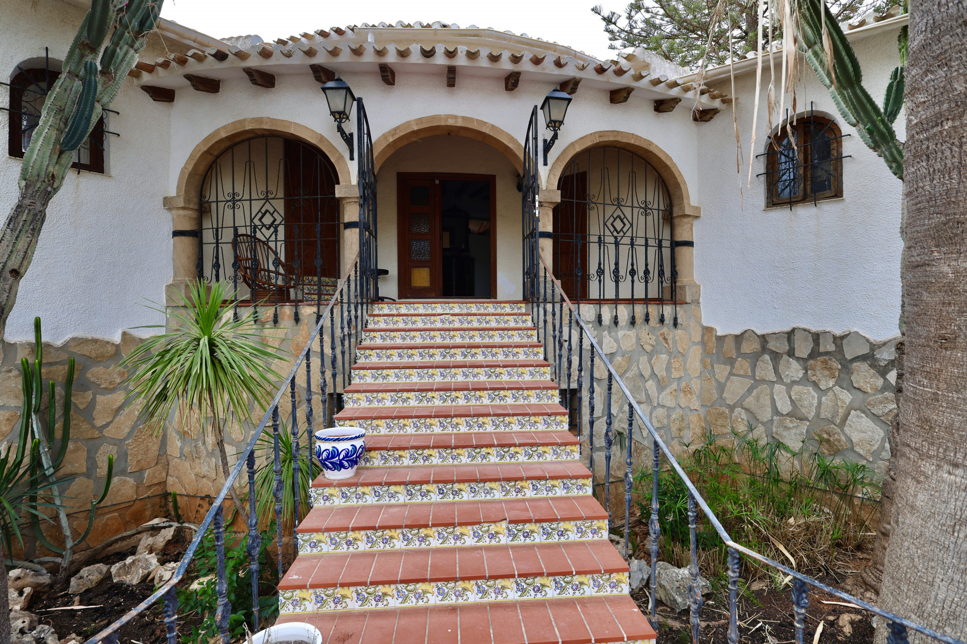 Haupteingang der Villa mit Terrakotta-Stufen und floralen Details.