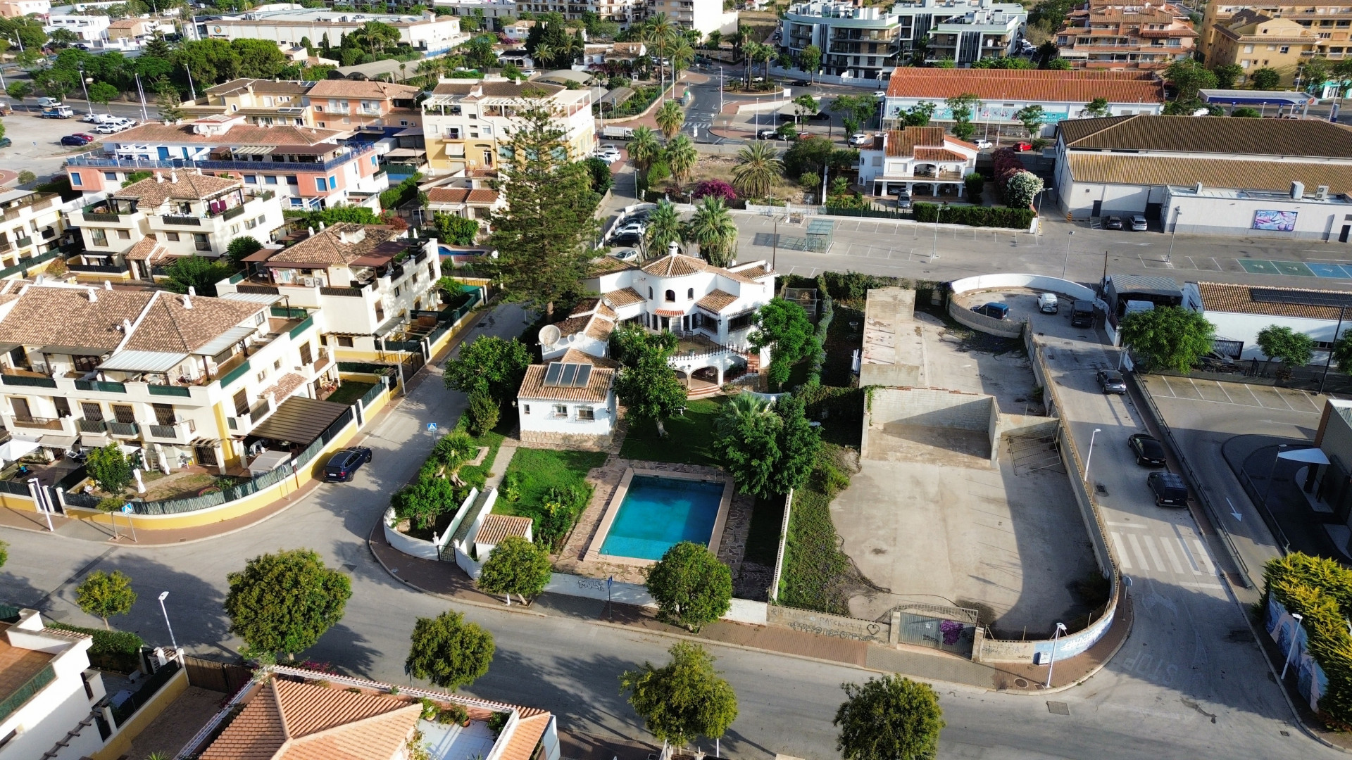 Luftaufnahme der Villa mit blauem Pool, umgeben von Gärten und Stadtgebäuden in Jávea.