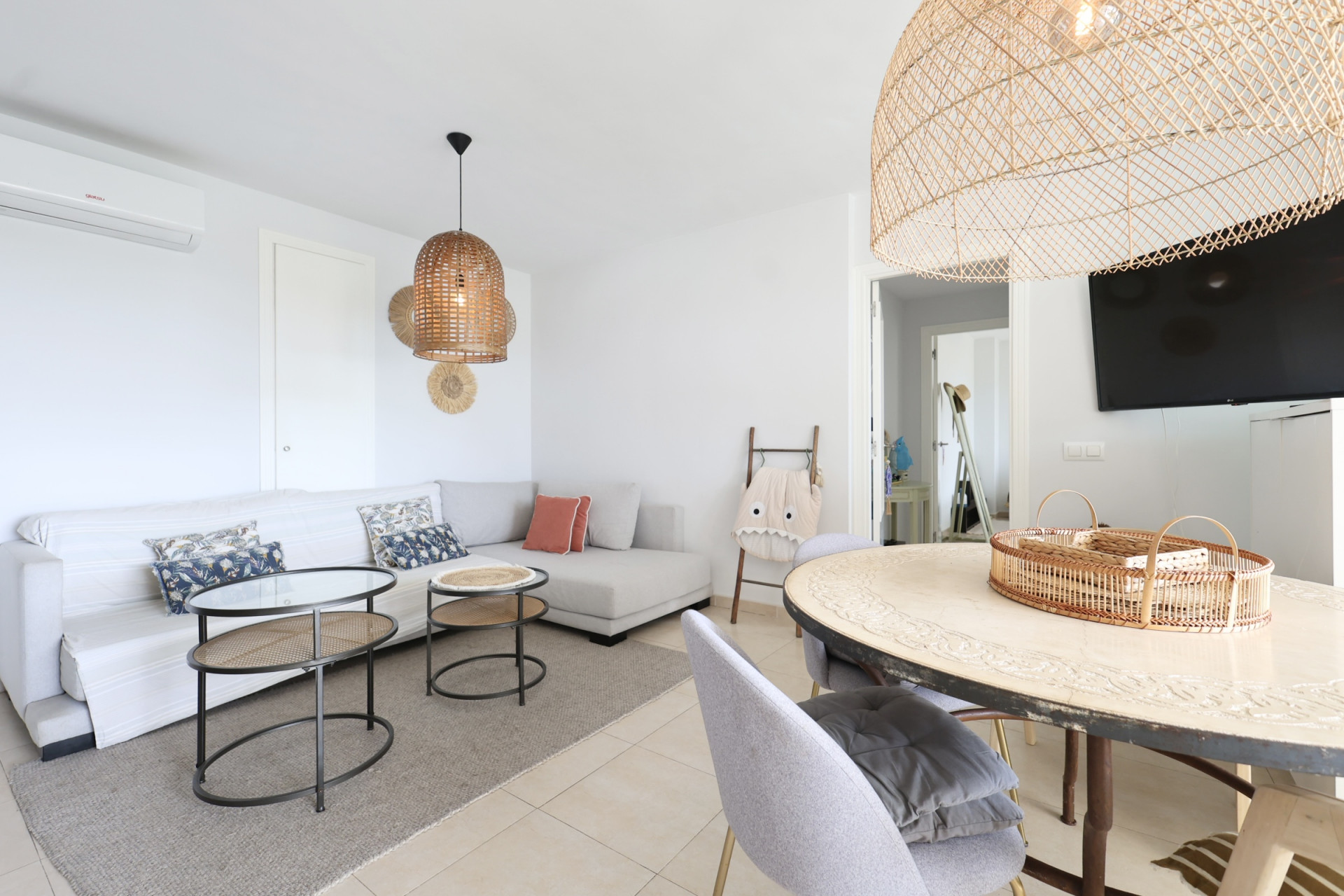 Helles Wohn-Esszimmer mit Ecksofa, Korblampen und Designer-Couchtisch.