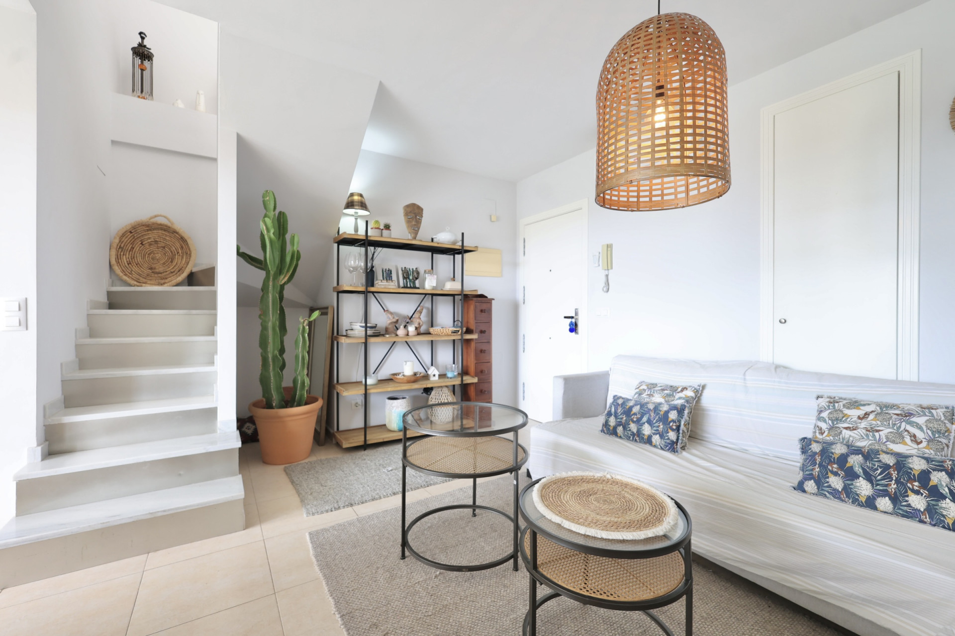 Helles Wohnzimmer mit Treppe zum Maisonette, minimalistischem Dekor und einer Pendelleuchte aus Korbgeflecht.