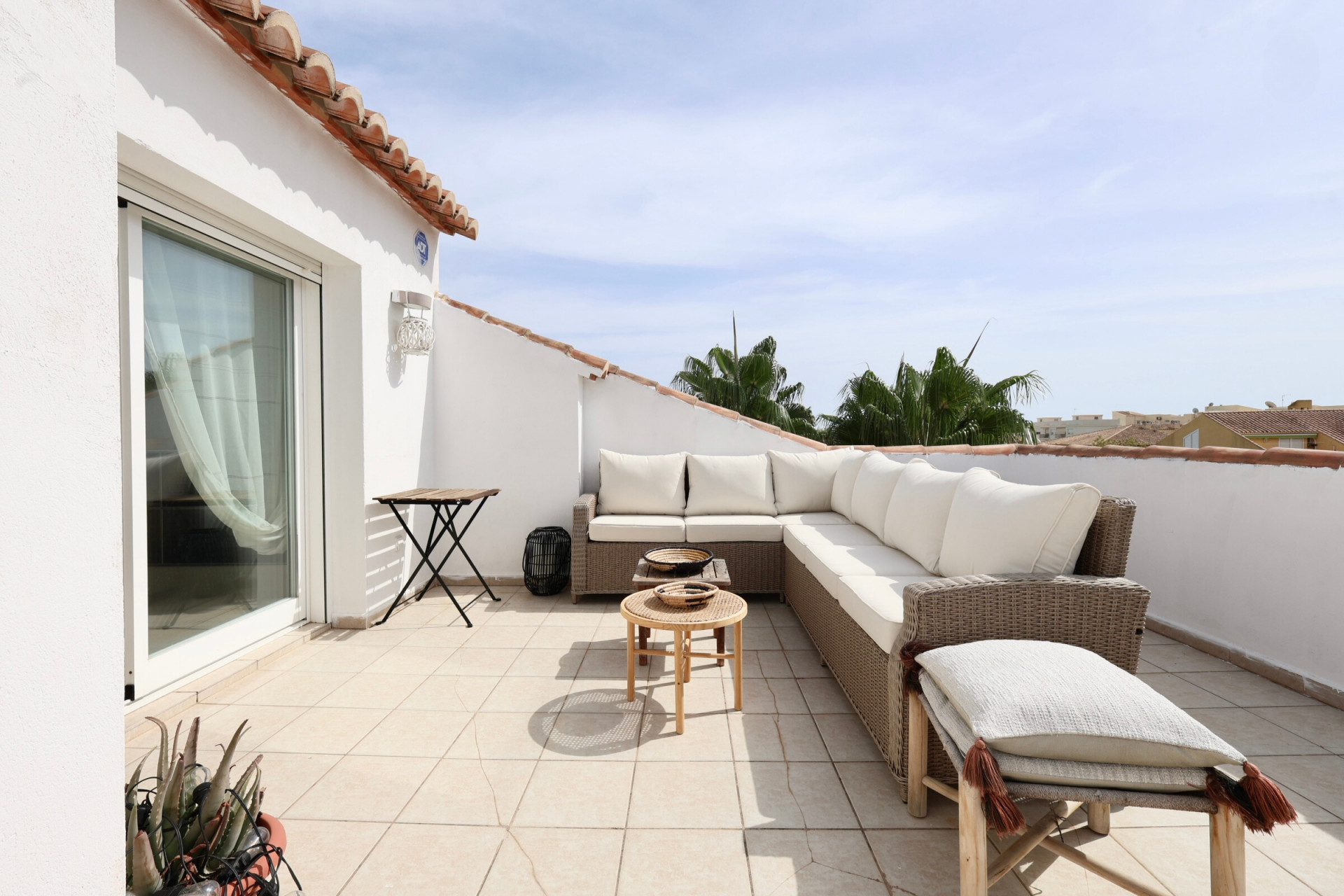 Sonnige Terrasse mit Rattanmöbeln und teilweisem Blick auf den Horizont.