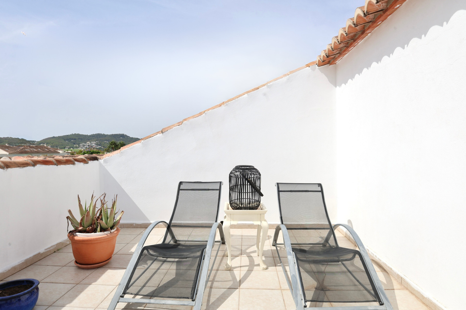 Terrasse mit zwei Sonnenliegen aus Metall, Beistelltisch und Bergblick.