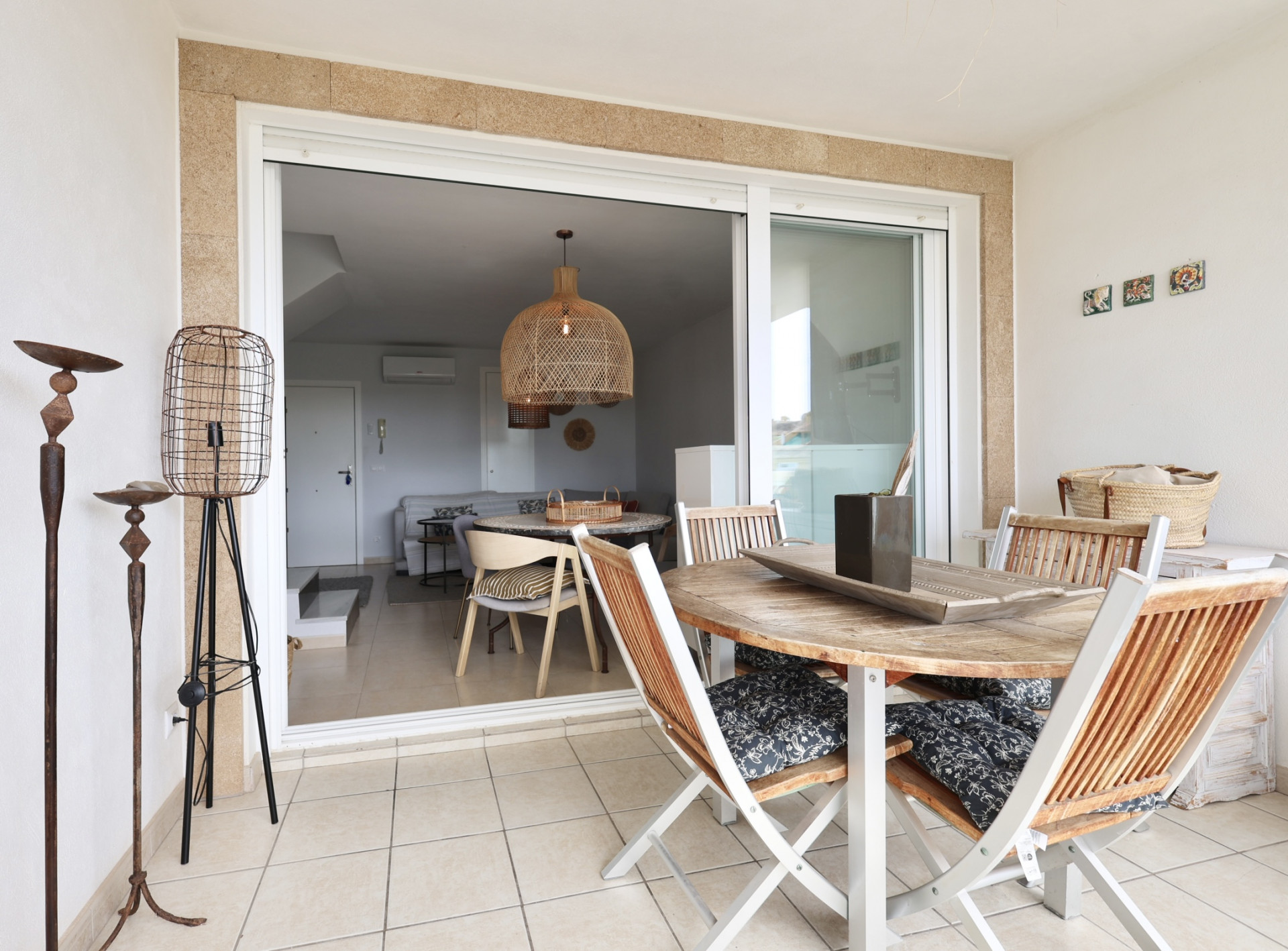 Überdachte Terrasse mit Holztisch und Klappstühlen mit gemusterten Kissen.