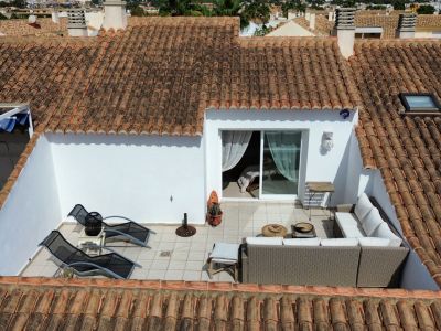 Erhöhte Ansicht der sonnendurchfluteten Terrasse mit Gartenmöbeln und Zugang zum Innenraum.