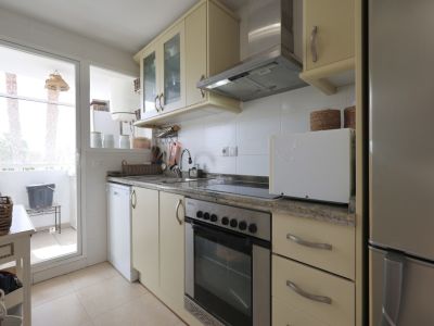 Helle Küche mit Granit-Arbeitsplatten, Edelstahlgeräten und Zugang zum Balkon.