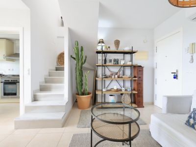 Helles Interieur mit weißer Treppe, Holz- und Metallregal und Couchtisch aus Rattan.
