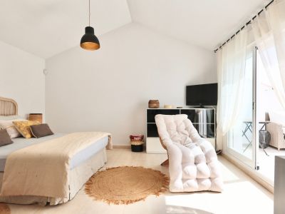 Helles Schlafzimmer mit Rattanbett, Juteteppich und Zugang zur Terrasse.