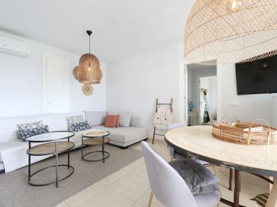 Helles Wohn-Esszimmer mit Ecksofa, Korblampen und Designer-Couchtisch.