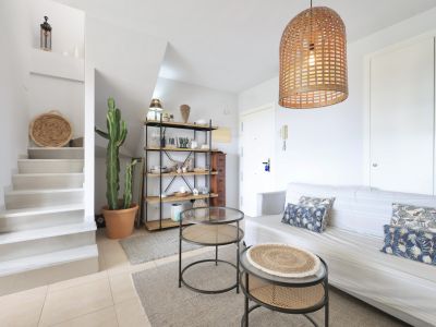 Helles Wohnzimmer mit Treppe zum Maisonette, minimalistischem Dekor und einer Pendelleuchte aus Korbgeflecht.