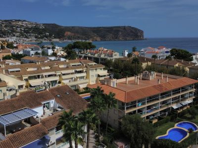 Luftaufnahme der Urbanisation mit Pool und Wohngebäuden mit roten Ziegeln in der Nähe der Küste von Jávea.