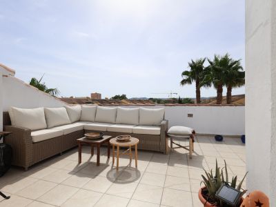 Sonnige, geflieste Terrasse mit Korbsitzgruppe und Blick auf Palmen.