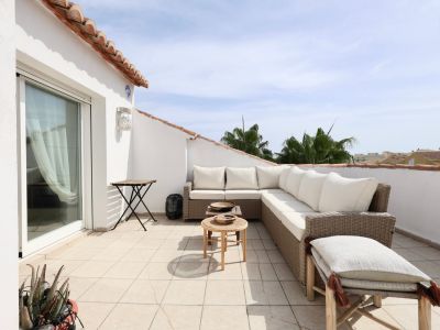Sonnige Terrasse mit Rattanmöbeln und teilweisem Blick auf den Horizont.