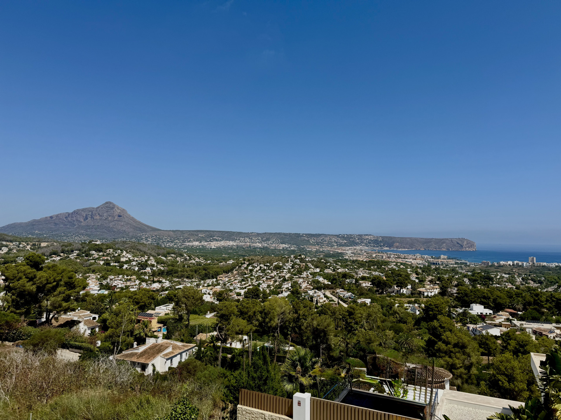 Panoramablick auf Jávea mit dem majestätischen Montgó, dem Mittelmeer und der grünen Stadtlandschaft unter klarem Himmel.