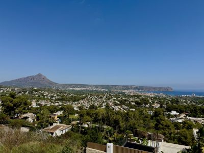 Panoramablick auf Jávea mit dem majestätischen Montgó, dem Mittelmeer und der grünen Stadtlandschaft unter klarem Himmel.