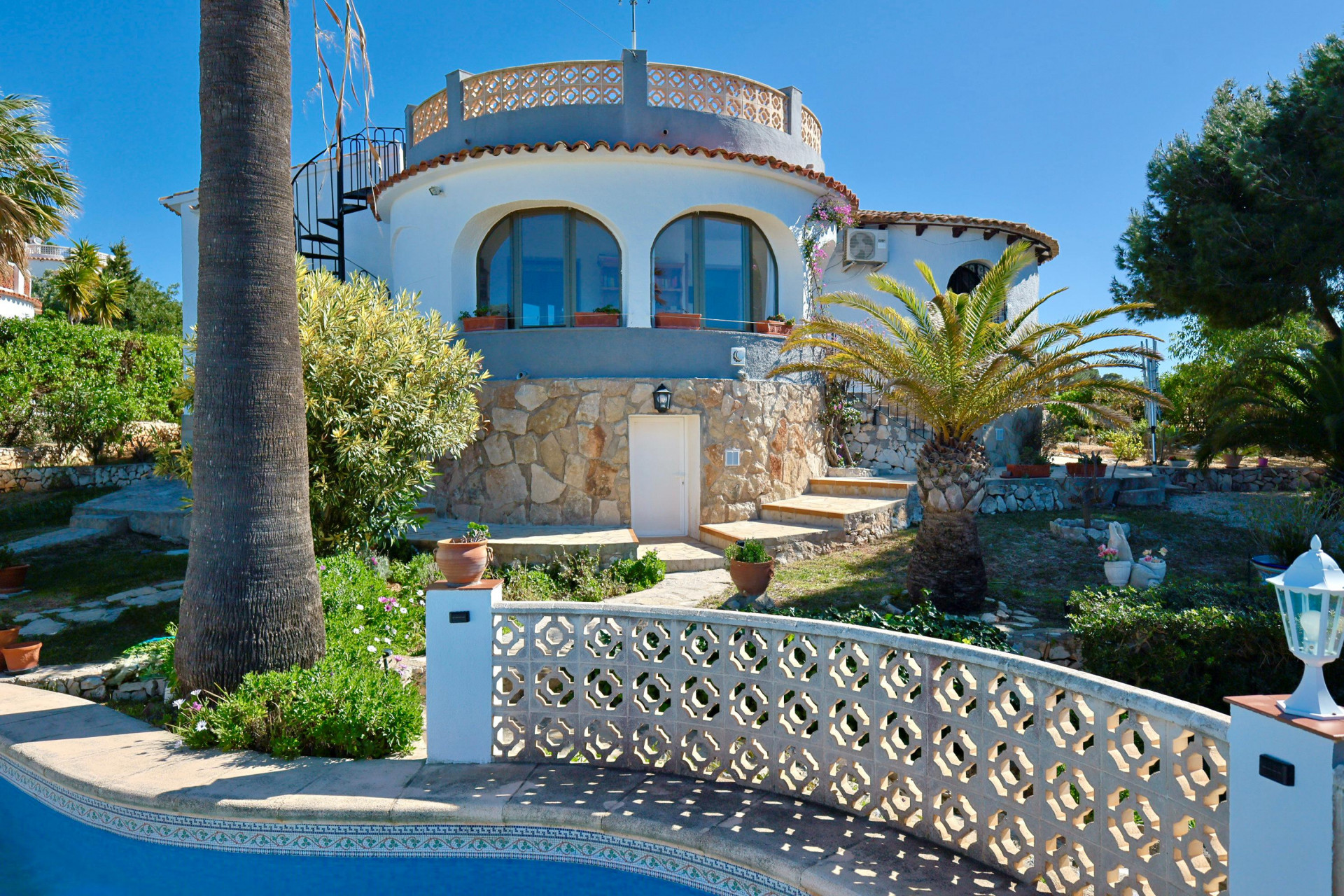 Außenansicht der Villa mit Pool und Steinfassade, umgeben von mediterranen Gärten.