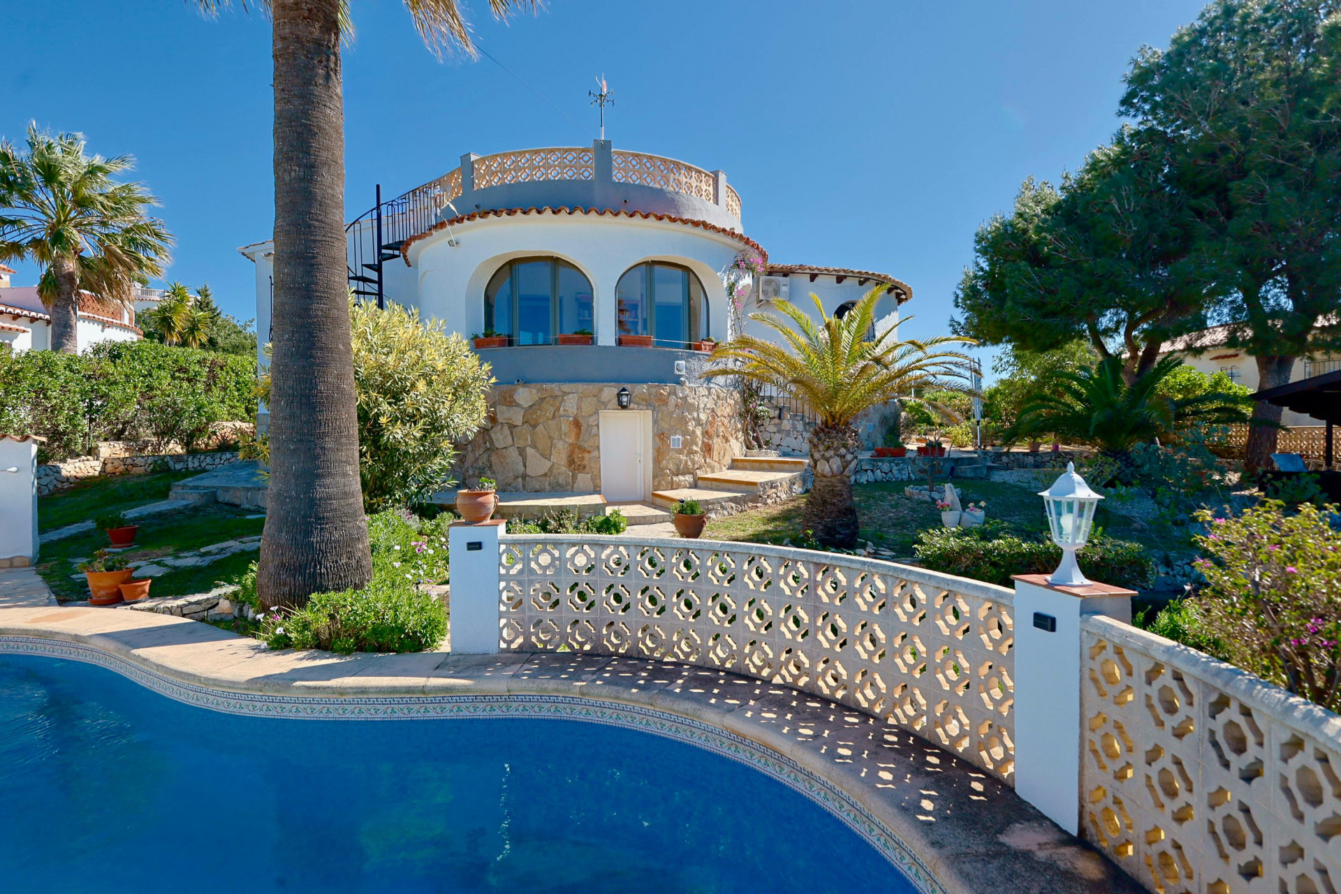 Blick auf den Pool mit Gittergeländer und Steinfassade der Villa in Jávea.