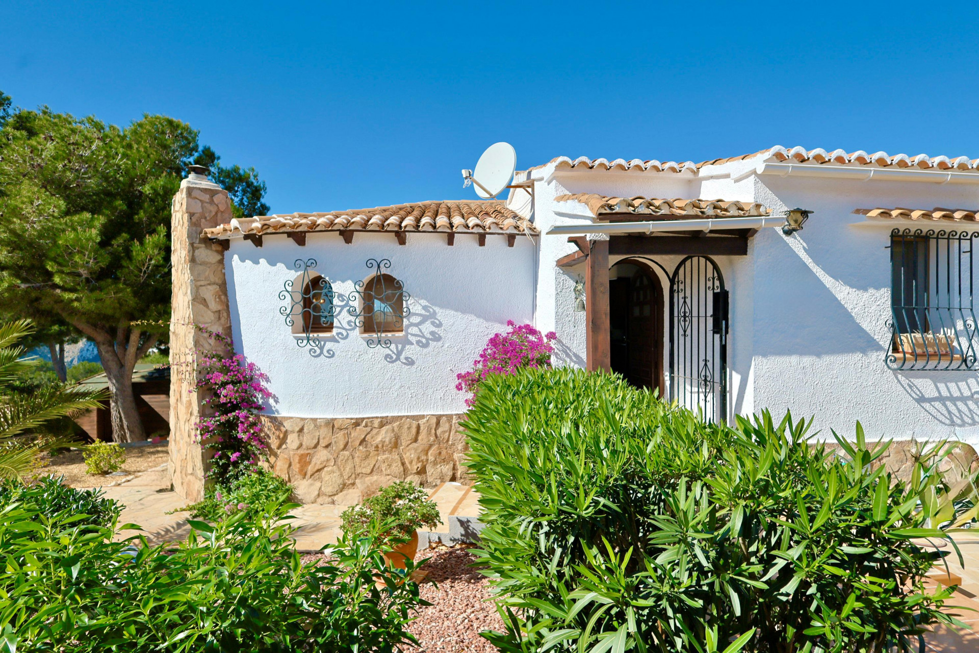 Fassade einer mediterranen Villa mit Steindetails, Dachziegeln und Zierbeschlägen.