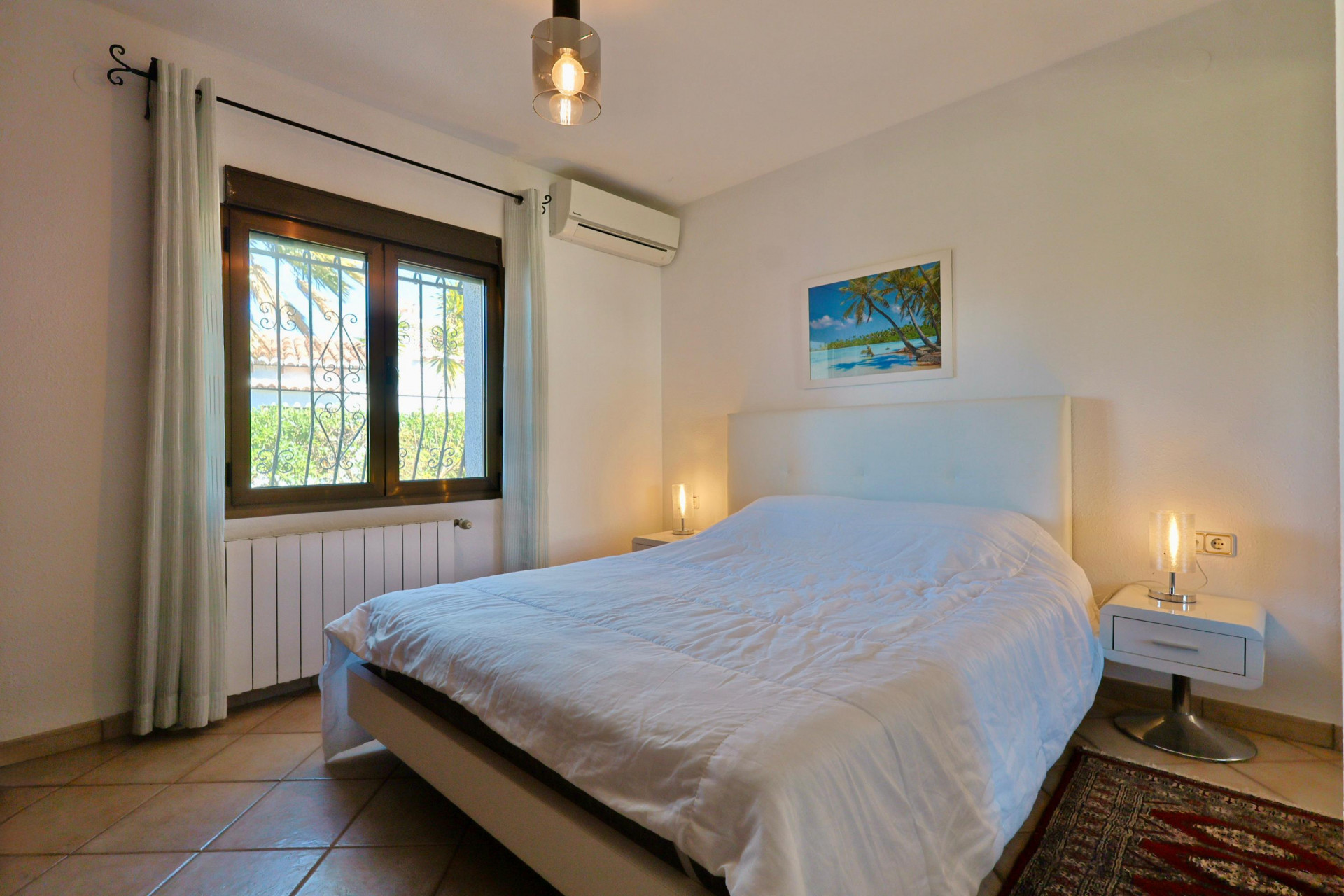 Helles Schlafzimmer mit Doppelbett, modernen Nachttischen und Fenster mit Blick nach draußen.