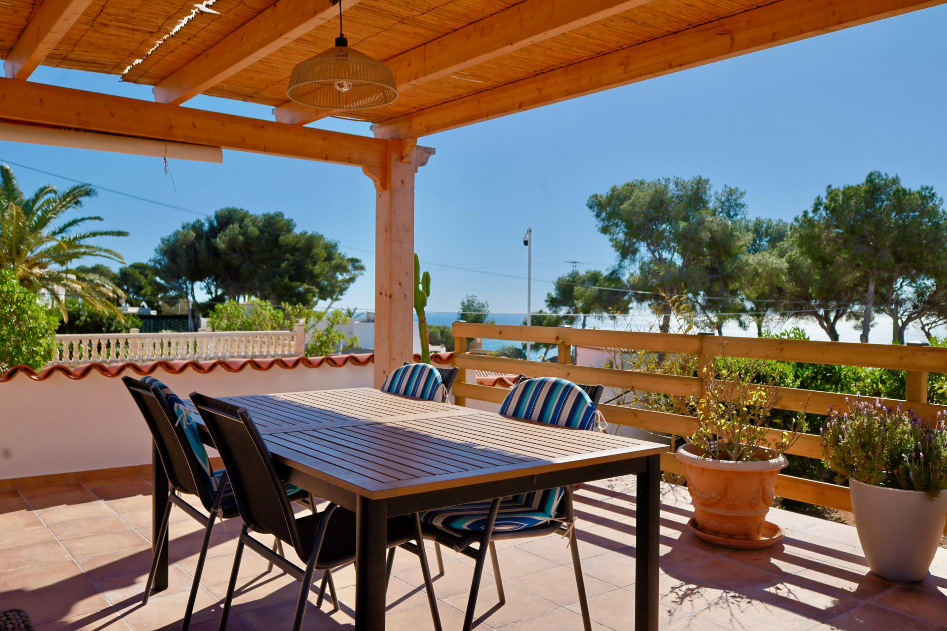 Überdachte Terrasse mit Esstisch und Blick auf das Mittelmeer.